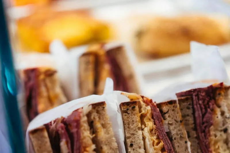 Sandwiches with meat and cheese in a glass deli display case