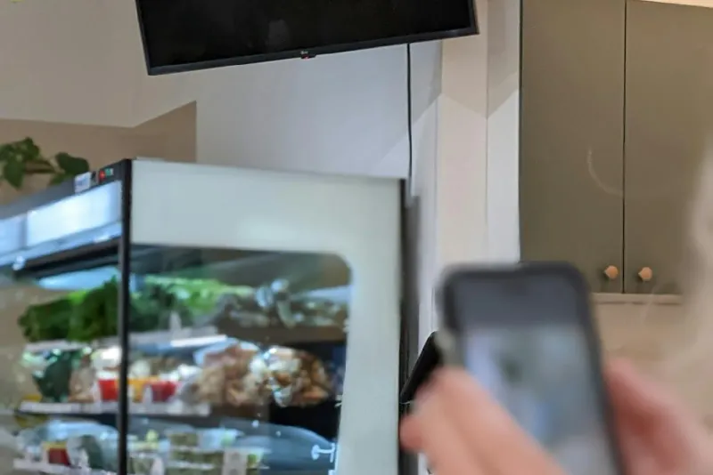A shopper holding a phone near a refrigerated fresh food display